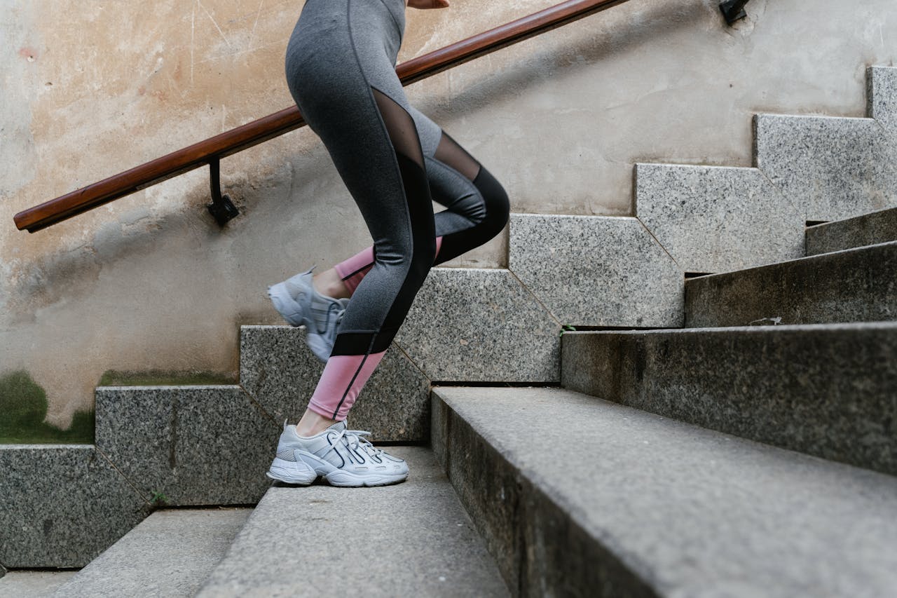 Woman engaging in fitness activity by running up concrete stairs outdoors.